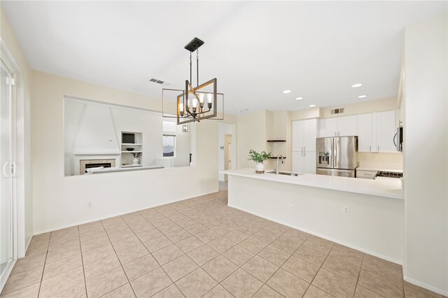 kitchen with pendant lighting, stainless steel fridge, an inviting chandelier, white cabinets, and kitchen peninsula