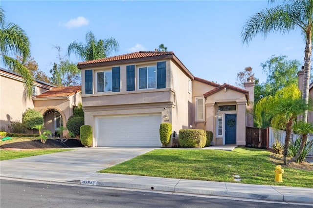 mediterranean / spanish house featuring stucco siding, a front lawn, driveway, a garage, and a tiled roof