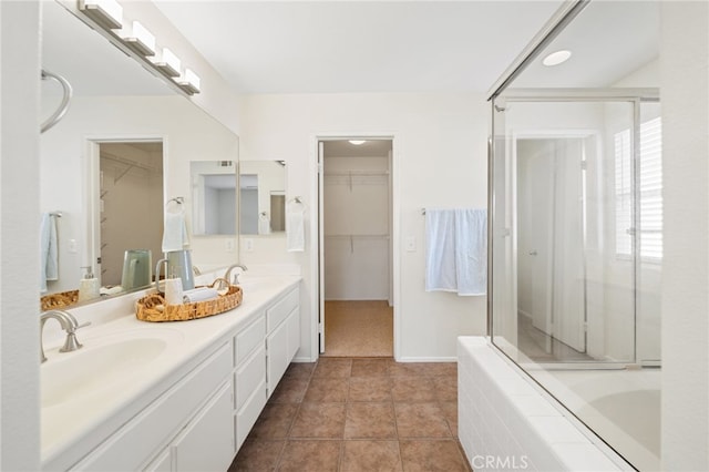 bathroom with tiled tub, vanity, and tile patterned flooring