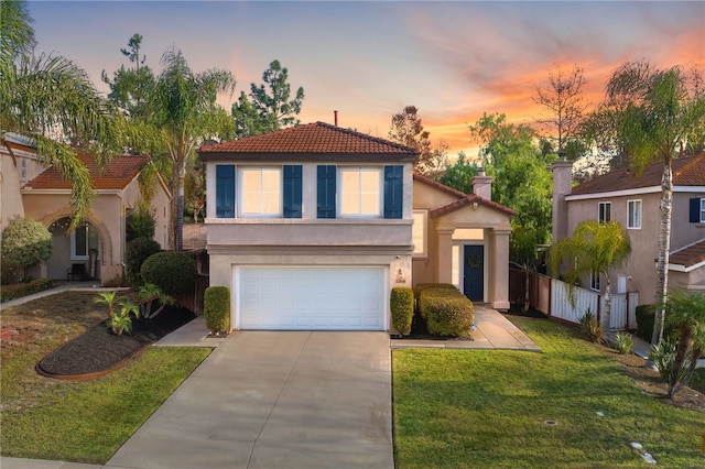 view of front of home with stucco siding, a lawn, fence, concrete driveway, and an attached garage