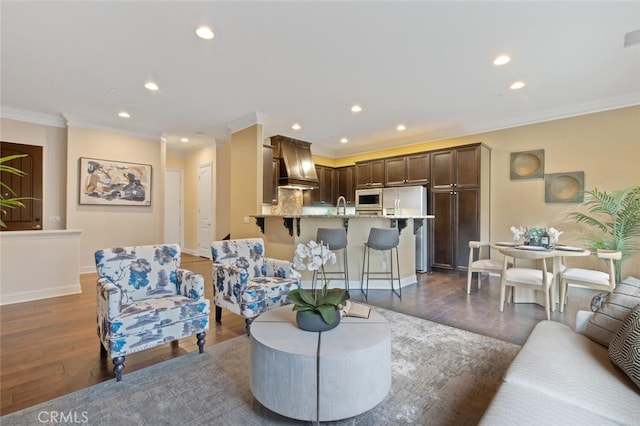 living room with dark wood-type flooring, sink, and crown molding