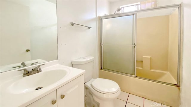 full bathroom with combined bath / shower with glass door, vanity, tile patterned floors, and toilet