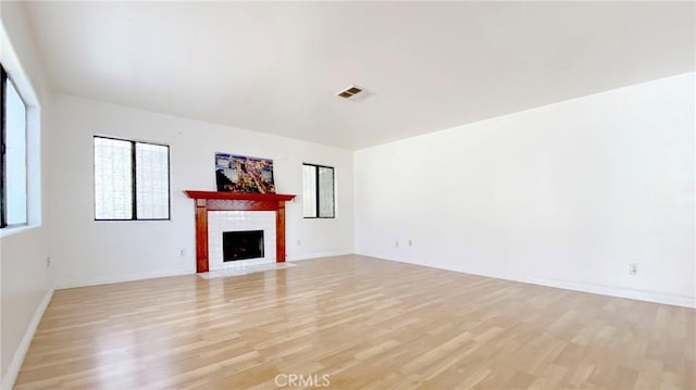 unfurnished living room featuring a brick fireplace and light wood-type flooring