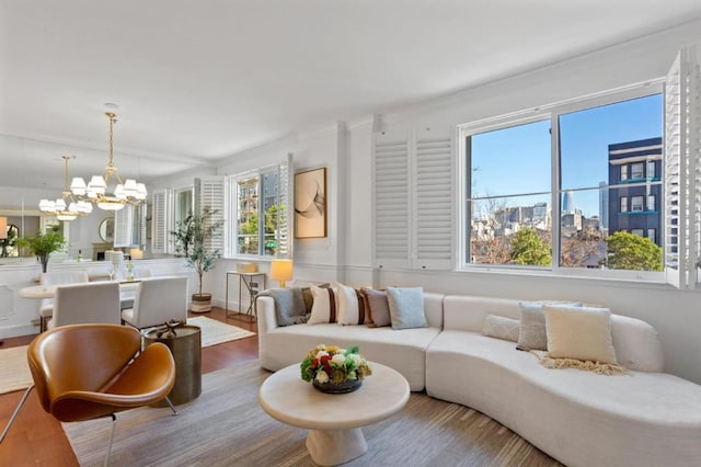 living room featuring crown molding, a healthy amount of sunlight, an inviting chandelier, and hardwood / wood-style flooring