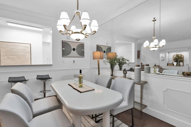 dining space featuring dark wood-type flooring, ornamental molding, and a notable chandelier