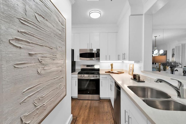 kitchen with white cabinetry, stainless steel appliances, hanging light fixtures, crown molding, and sink