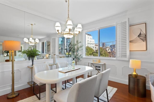 dining space with wood-type flooring, ornamental molding, and a notable chandelier