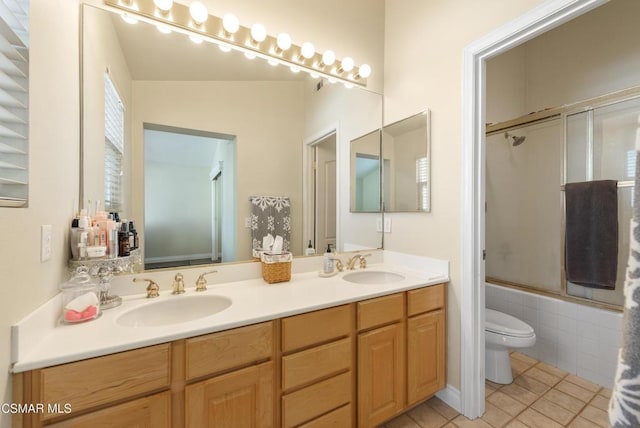 full bathroom featuring toilet, bath / shower combo with glass door, tile patterned flooring, and vanity