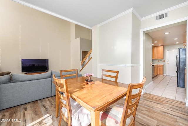 dining space with light wood-type flooring and ornamental molding