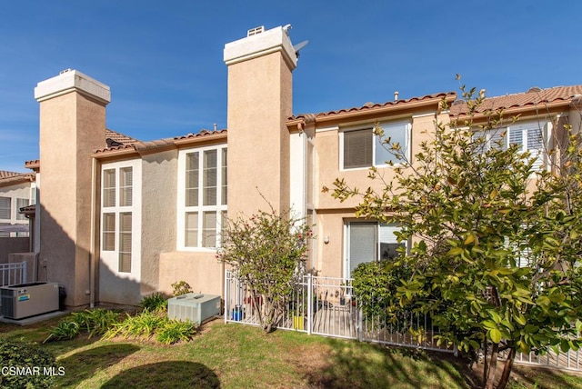 rear view of house with central air condition unit and a yard