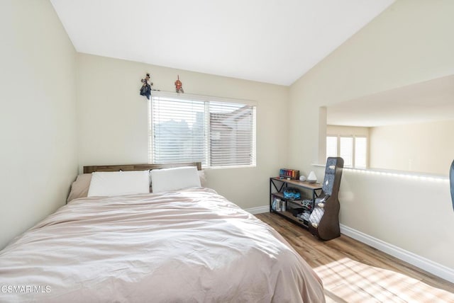 bedroom with lofted ceiling and light hardwood / wood-style floors