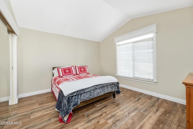 bedroom with lofted ceiling and light wood-type flooring