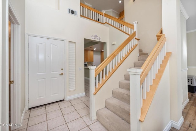 tiled foyer with ornamental molding and a towering ceiling