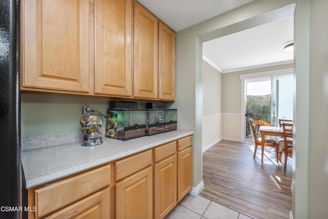 kitchen with light tile patterned floors, light brown cabinetry, and ornamental molding