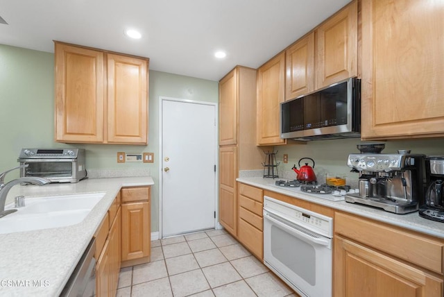 kitchen with light tile patterned flooring, stainless steel appliances, light brown cabinets, and sink