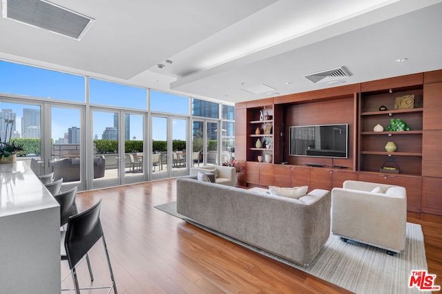 living room featuring expansive windows, french doors, built in features, and light hardwood / wood-style flooring