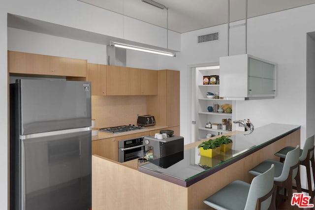 kitchen featuring decorative light fixtures, stainless steel appliances, backsplash, kitchen peninsula, and a breakfast bar