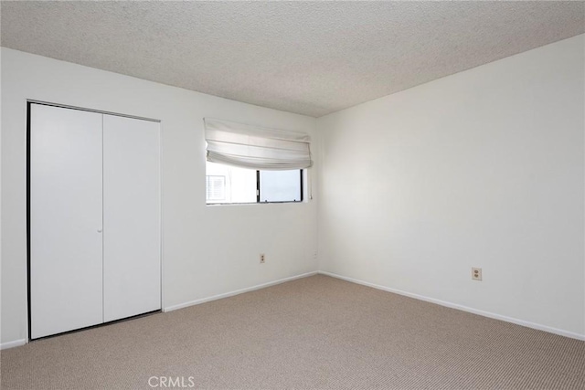 unfurnished bedroom featuring light carpet, a closet, and a textured ceiling