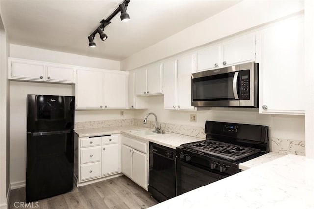 kitchen with white cabinets, black appliances, track lighting, light hardwood / wood-style floors, and sink