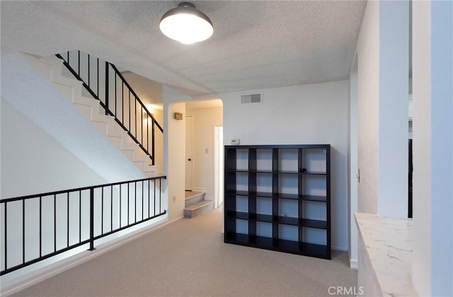 hall with light carpet and a textured ceiling