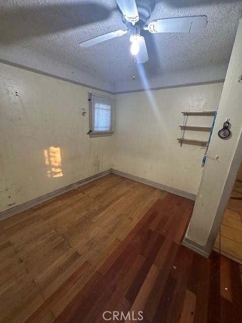 basement featuring a textured ceiling, ceiling fan, and dark hardwood / wood-style floors