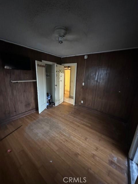 unfurnished bedroom featuring wood walls and hardwood / wood-style floors