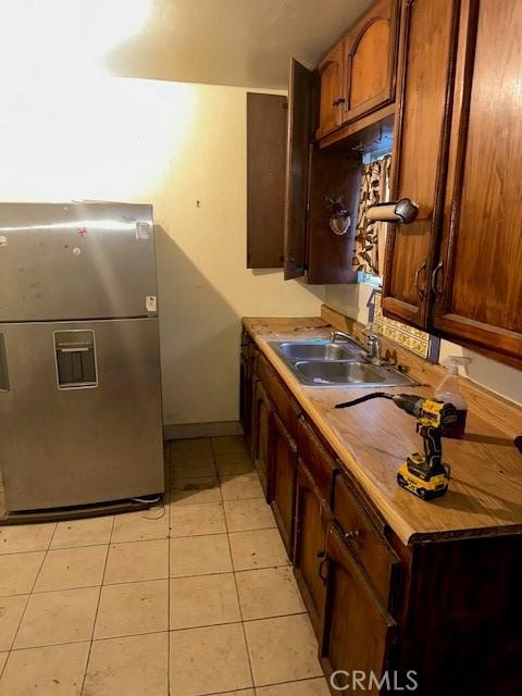 kitchen featuring stainless steel fridge with ice dispenser, light tile patterned floors, and sink