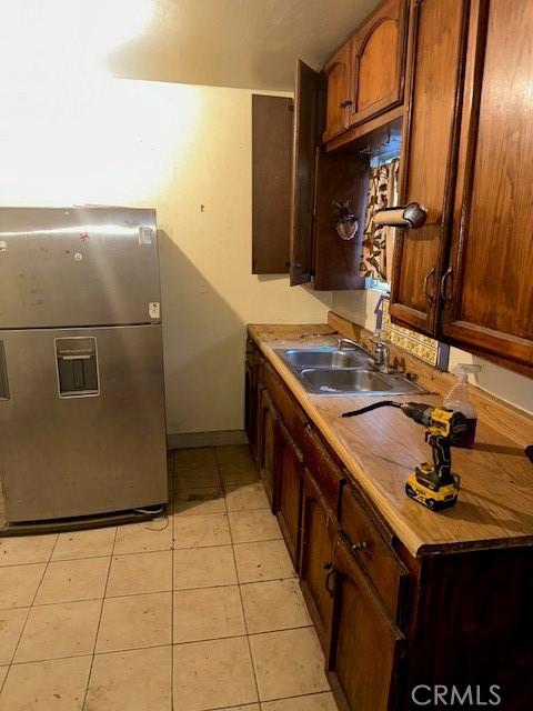 kitchen with light tile patterned floors, stainless steel fridge, and sink