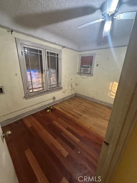 unfurnished room featuring a textured ceiling, ceiling fan, cooling unit, and hardwood / wood-style floors