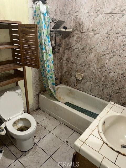 full bathroom featuring tile patterned flooring, toilet, vanity, and shower / tub combo with curtain