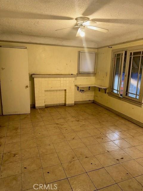 unfurnished room with ceiling fan and a textured ceiling