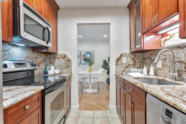 kitchen with light stone counters, sink, light tile patterned floors, and appliances with stainless steel finishes