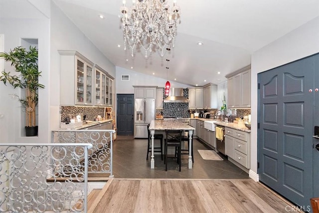 kitchen featuring a kitchen bar, appliances with stainless steel finishes, vaulted ceiling, a kitchen island, and pendant lighting