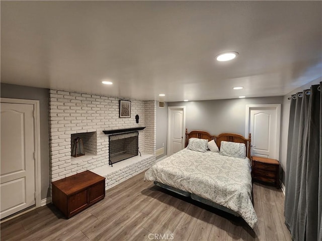 bedroom with a fireplace and hardwood / wood-style flooring