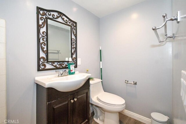 bathroom with wood-type flooring, toilet, and vanity