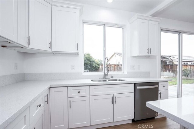 kitchen with a wealth of natural light, white cabinetry, dishwasher, and sink