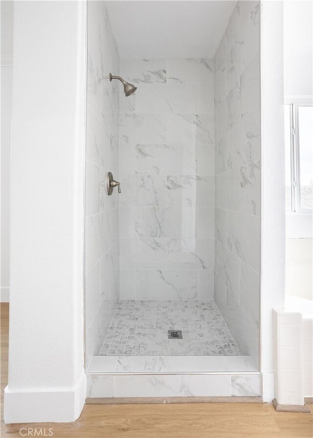 bathroom featuring hardwood / wood-style flooring and a tile shower