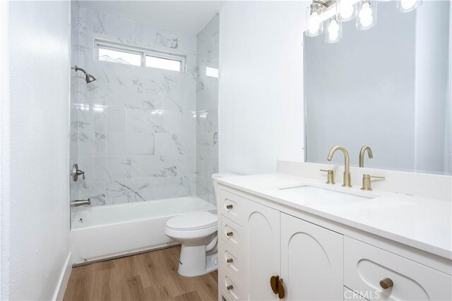 full bathroom featuring toilet, tiled shower / bath combo, hardwood / wood-style flooring, and vanity