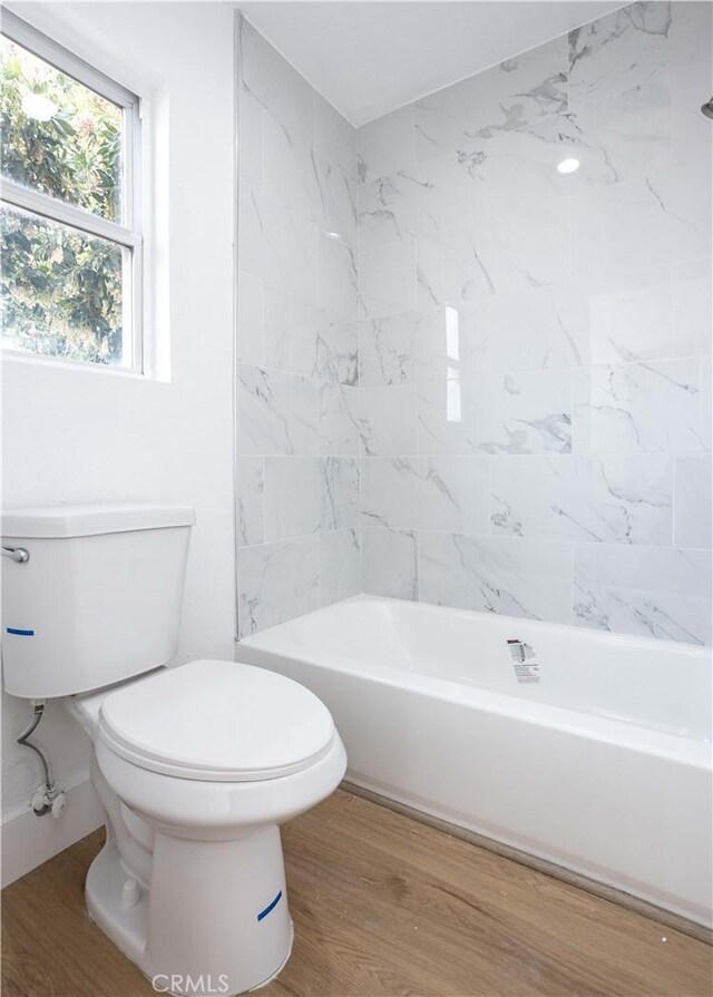 bathroom featuring toilet,  shower combination, and hardwood / wood-style floors