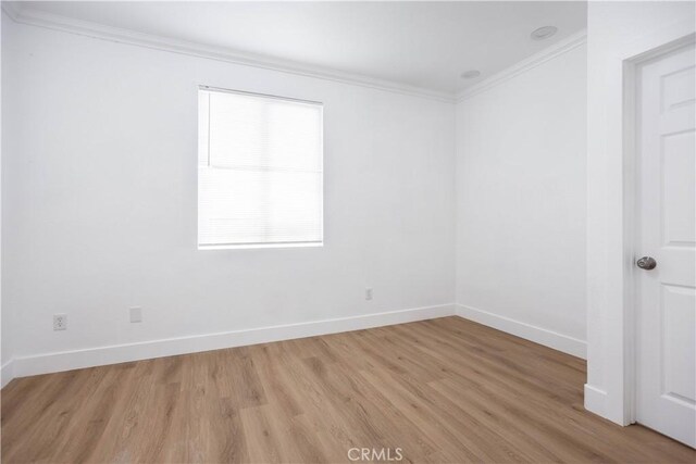 empty room with crown molding and light hardwood / wood-style flooring