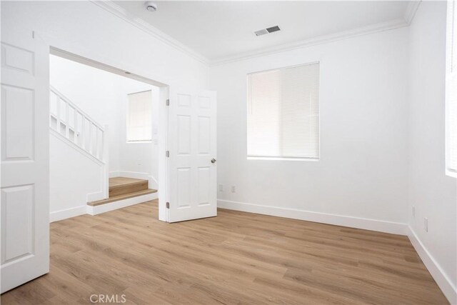 spare room featuring light wood-type flooring and crown molding