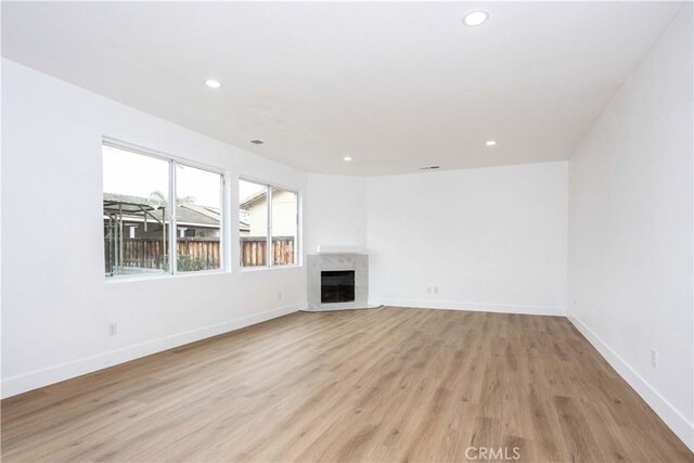 unfurnished living room featuring a premium fireplace and light hardwood / wood-style floors