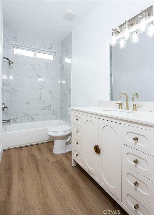 full bathroom featuring hardwood / wood-style flooring, toilet, vanity, and tiled shower / bath combo