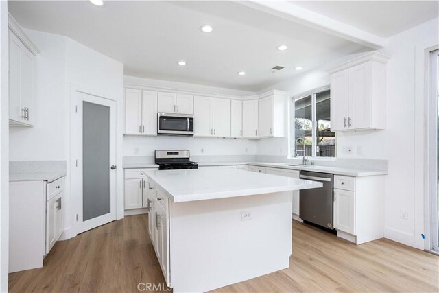 kitchen featuring a kitchen island, sink, white cabinetry, light hardwood / wood-style flooring, and stainless steel appliances