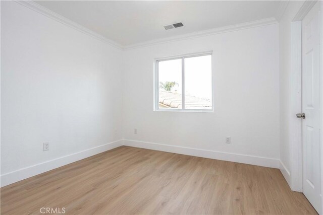 empty room with ornamental molding and light wood-type flooring