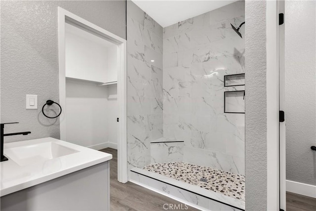 bathroom featuring a tile shower, vanity, and hardwood / wood-style flooring