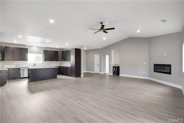 unfurnished living room featuring ceiling fan, lofted ceiling, sink, and light hardwood / wood-style floors