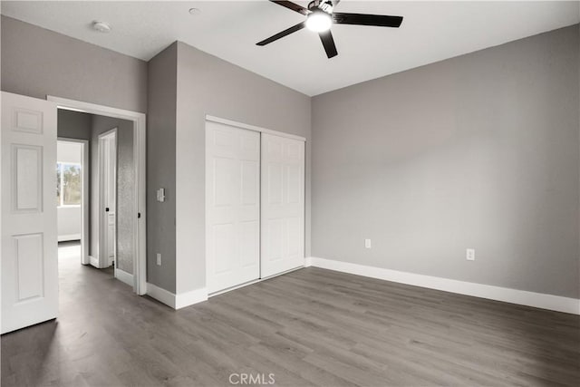 unfurnished bedroom featuring ceiling fan, dark hardwood / wood-style floors, and a closet