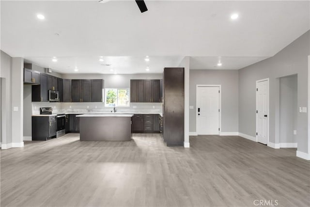 kitchen with ceiling fan, stainless steel appliances, a kitchen island, and light hardwood / wood-style flooring