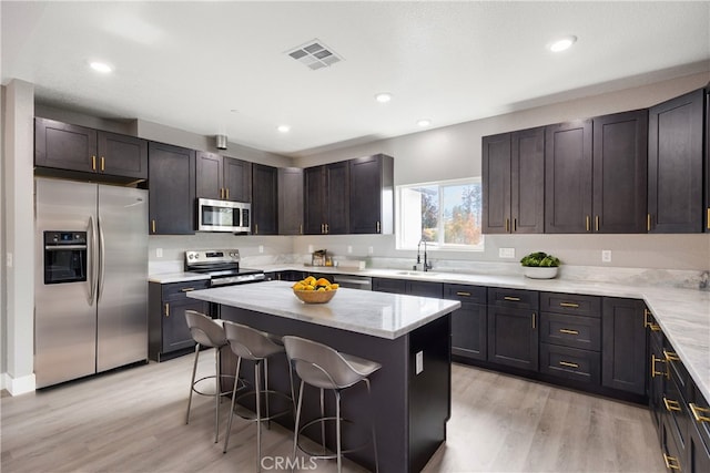 kitchen featuring a kitchen island, appliances with stainless steel finishes, sink, a kitchen breakfast bar, and dark brown cabinetry